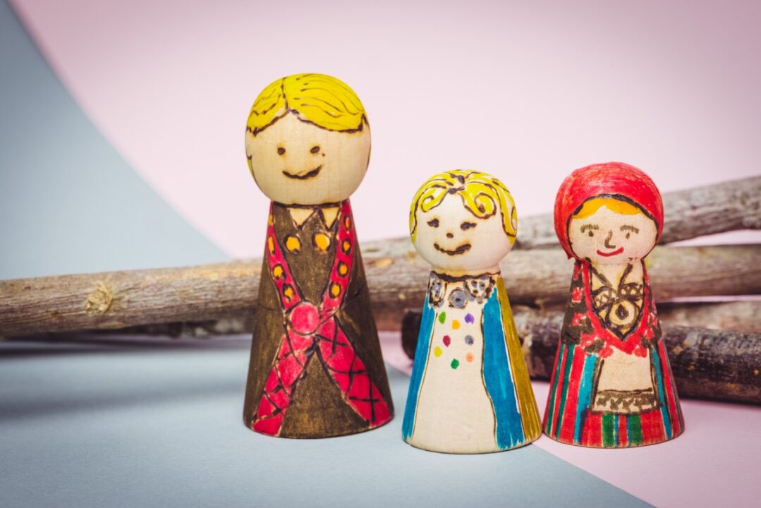 Kolm värvikalt maalitud puidust nukk-figuuri rivis.