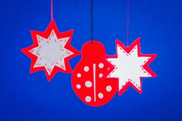 Kolm helkurit rippumas sinisel taustal. Kaks helkurit on tähekujulised ja üks helkur lepatriinukujuline.