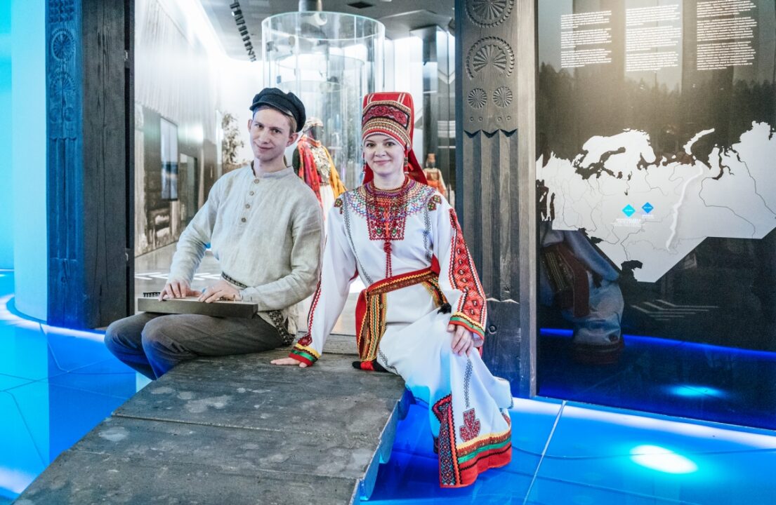 Mees ja naine istumas  rahvuslikus riietuses. Valgusküllane keskkond.